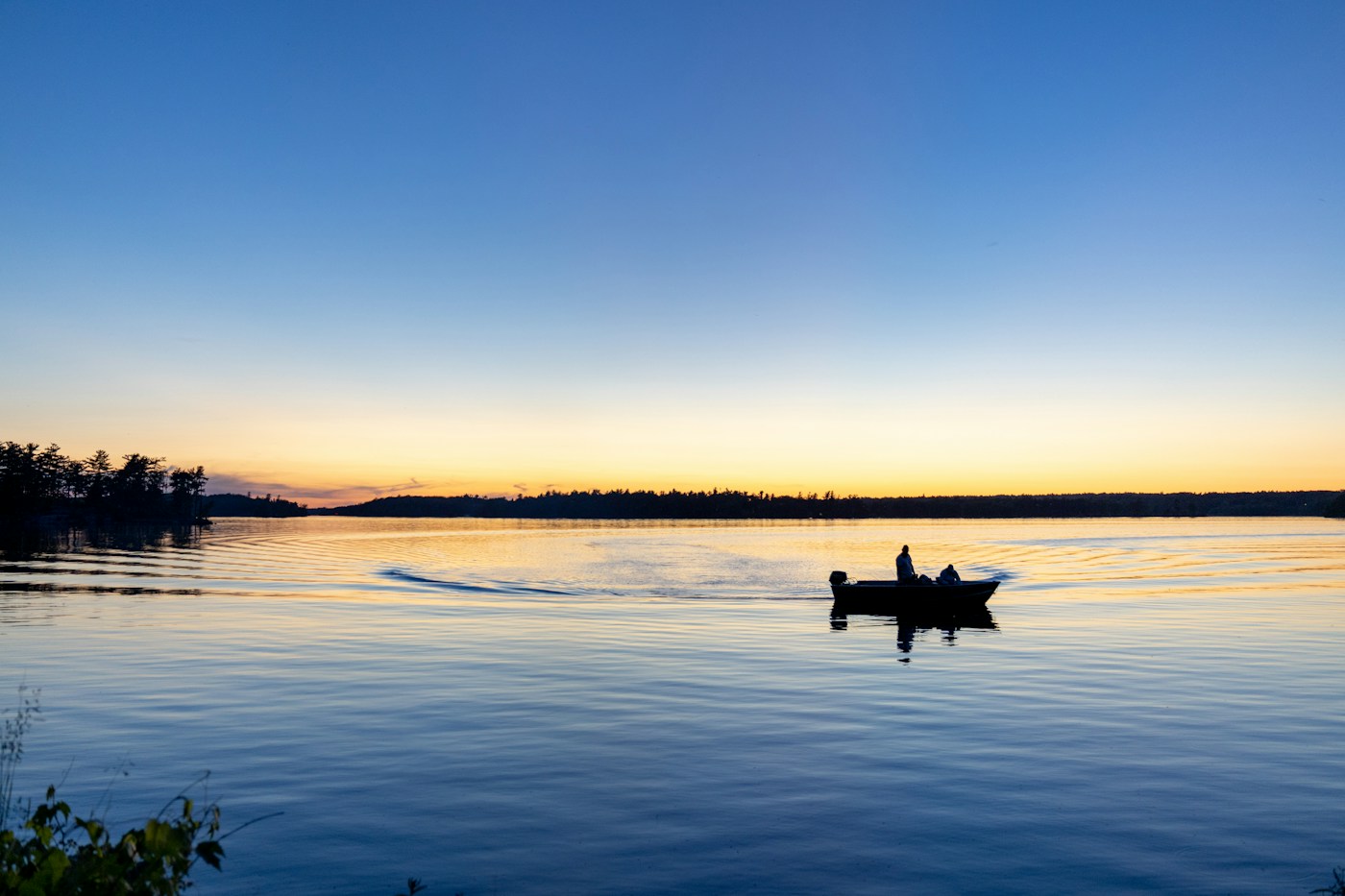 A boat on a still lake at sunset